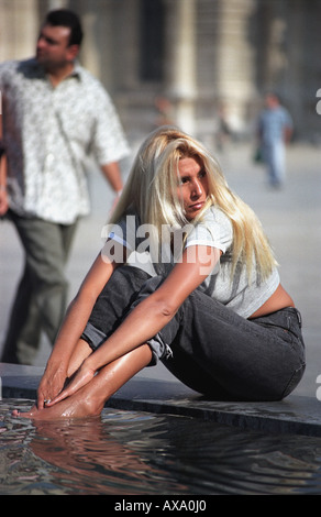 Fille blonde ses pieds de refroidissement dans l'un des I.M.Pei's dispose de l'eau, le Louvre, Paris Banque D'Images