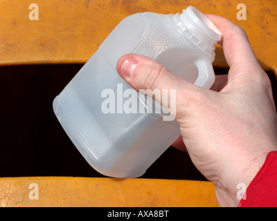 Mans part plaçant une pinte opaque vide recyclable bouteille en plastique HDPE de lait dans un bac de recyclage au centre de recyclage de matières plastiques Banque D'Images