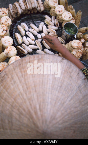Femme portant chapeau conique vendre Snack food Cantho Delta du Mékong Vietnam Banque D'Images
