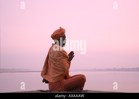 Saint homme méditer sur la rive du fleuve du Gange Varanasi Inde Banque D'Images