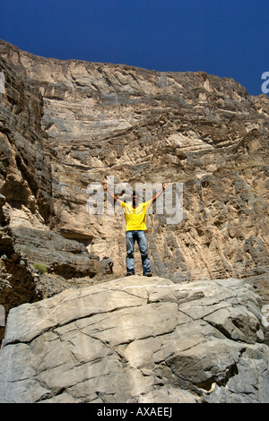 Un homme dans une chemise jaune du Wadi Nakhr, près de l'Oued Ghool à Jebel Akhdar dans l'Ouest de montagnes Hajar du sultanat d'Oman. Banque D'Images