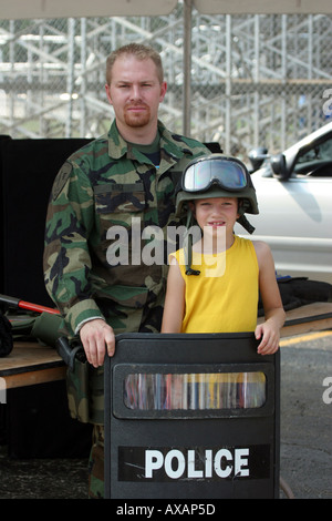 Agent de police de camouflage avec boy holding une protection de la police et le port d'un casque Banque D'Images