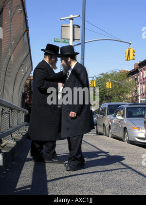 Les hommes juifs en vêtements traditionnels chatter sur le trottoir, États-Unis d'Amérique, Brooklyn, New York Banque D'Images