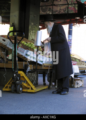 L'homme juif en vêtements traditionnels d'acheter des fruits, des États-Unis d'Amérique, Brooklyn, New York Banque D'Images