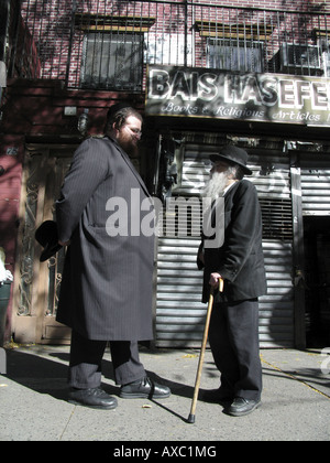 Un très grand et un peu d'homme juif en vêtements traditionnels chatter sur le trottoir, États-Unis d'Amérique, Brooklyn, New York Banque D'Images