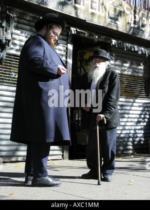 Un très grand et un peu d'homme juif en vêtements traditionnels chatter sur le trottoir, États-Unis d'Amérique, Brooklyn, New York Banque D'Images