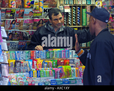 Vendeur en kiosque entouré par des biens d'une conversation avec un client, USA, Manhattan, New York Banque D'Images