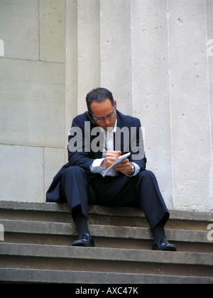 L'homme d'affaires parler sur son téléphone cellulaire et prendre des notes près de la Bourse de New York à Wall Street, USA, Manhattan, New Y Banque D'Images