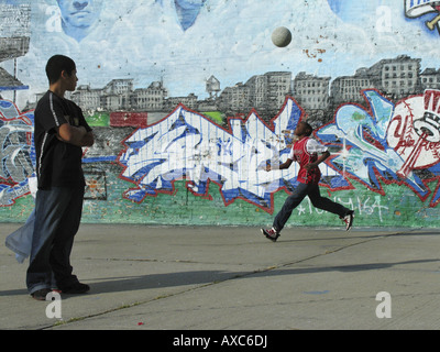 Garçons jouant au basket-ball sur un terrain de près d'un bâtiment avec des graffitis, Etats Unis, Bronx, New York Banque D'Images