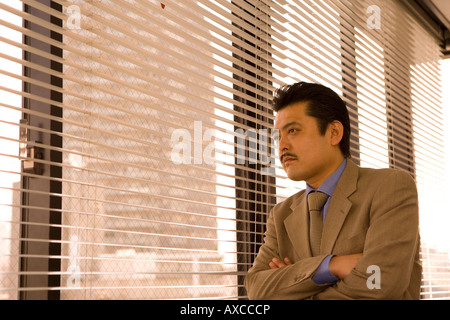 Businessman looking through blinds Banque D'Images