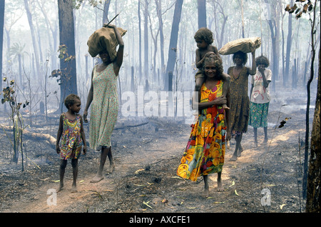 Les femmes autochtones de la collecte et de retour couleur feuilles comestibles en bois de fumer après bush fire ArnhemLand NT Australie centrale Banque D'Images