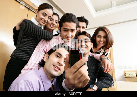 Low angle view of groupe de gens d'affaires en cliquant sur photo d'eux avec un téléphone mobile et souriant Banque D'Images