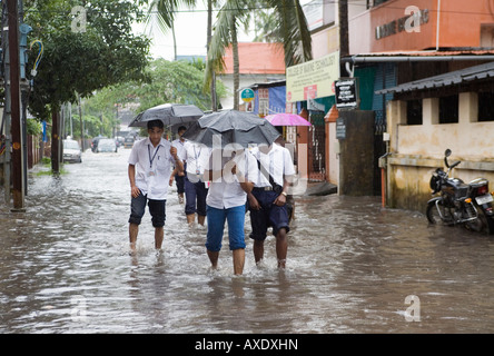 Les jeunes écoliers indiens à gué à l'école par le biais de routes inondées après effet pluie Ernakulam Kerala Inde du Sud Banque D'Images