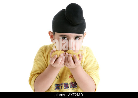 Portrait d'un Sikh boy eating laddu Banque D'Images