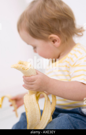 Baby Girl (2-3) peeling une banane Banque D'Images
