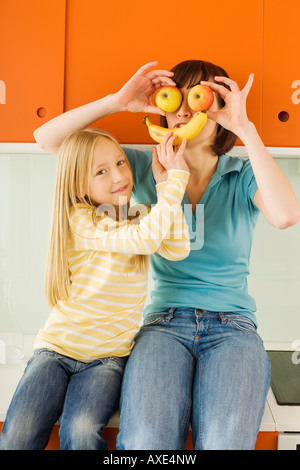 Mère et fille (8-9) dans la cuisine, mère holding apples devant ses yeux, Banque D'Images