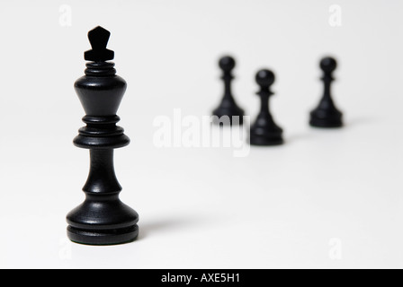 Les échecs, l'un roi noir se trouve en face d'un petit groupe de pions noirs, symbole de domination, de leadership Banque D'Images