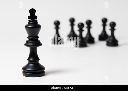 Les échecs, l'un roi noir se trouve en face d'un groupe de pions noirs, symbole de domination, de leadership Banque D'Images