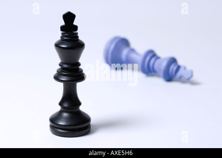 Les échecs, l'un roi noir se trouve en face d'un bleu roi tombé, symbole de victoire, défaite Banque D'Images