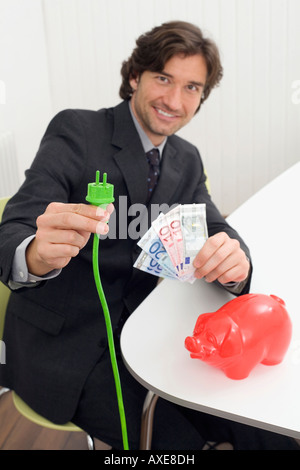 Man holding green plug et billets Banque D'Images