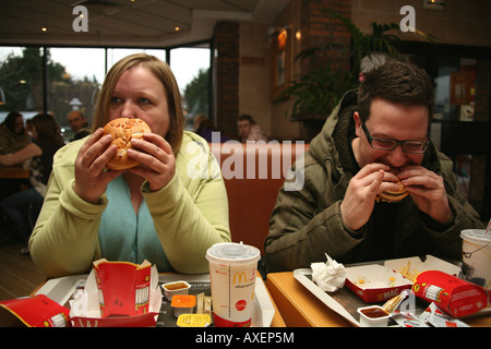 L'homme et des femmes et les copeaux eating burgers Banque D'Images