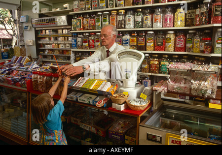 Un propriétaire d'une boutique de confiseries les mains sur un paquet de bonbons à une jeune fille de Frinton And Essex, UK Banque D'Images