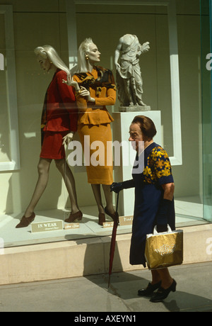 Mais une vieille dame smart shopper fait son chemin New Bond Street mannequins habillés avec élégance passée dans un magasin fenêtre avant. Banque D'Images