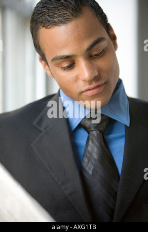 Jeune homme portant un costume et une cravate lire un journal Banque D'Images