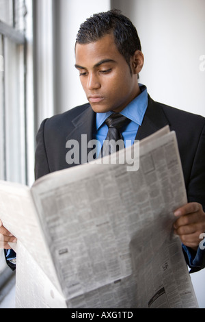 Jeune homme d'affaires de la lecture d'un papier de nouvelles Banque D'Images