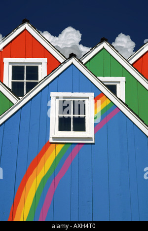 Combinent des petites maisons colorées en rouge, vert et bleu avec un arc-en-ciel peint sur le mur Banque D'Images