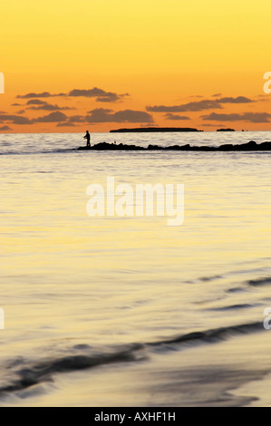 Silhouette d'un pêcheur La pêche dans la mer au coucher du soleil à Woodman Point, Perth, Australie occidentale Banque D'Images