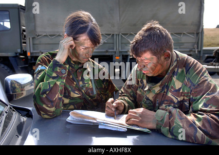 Une ARMÉE BRITANNIQUE FEMME RECRUTER VÉRIFIE UN SITE TOUT EN ÉTANT INFORMÉS PAR UN SERGENT DE LA COULEUR AVANT LA FORMATION D'UNE VITRE LORS D'UNE COUR DE SNIPER Banque D'Images