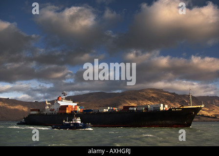 Un porte-conteneurs fait son chemin jusqu'à la chaîne sur la voie à son poste à quai au port de Lyttelton. Banque D'Images