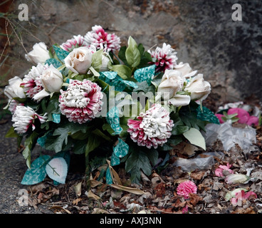 Close up de fleurs artificielles en plastique sur une tombe Banque D'Images