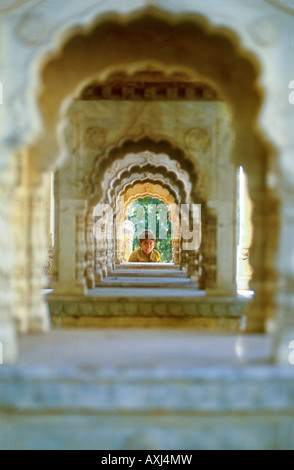 Jeune garçon indien à travers une rangée d'arches à la citadelle historique de Gaitore orange près de Jaipur, Rajasthan Banque D'Images