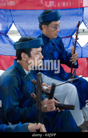 Deux musiciens habillés en ao dai traditionnel jouant des instruments traditionnels vietnamiens pour les esprits des défunts Banque D'Images