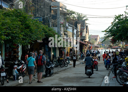 Scène de rue bordée d'arbres à Hoi An Vietnam montrant boutiques touristes parking pour vélos et motos. Respectueux des piétons Banque D'Images