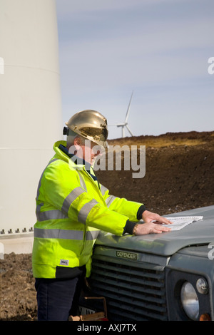 Révision du plan directeur. Un ingénieur de chantier de construction qui étudie les plans sur le capot de Land Rover, à Wind Farm installation, Écosse, Royaume-Uni Banque D'Images