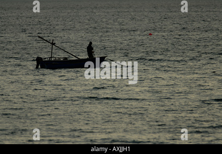 Un pêcheur dans un petit bateau transporte un pot dans la baie de St Ives tôt le matin Banque D'Images