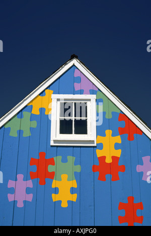 Little Blue House gable avec carré blanc peu de fenêtre et d'une scie sauteuse en pièces de puzzle couleurs arc-en-ciel Banque D'Images