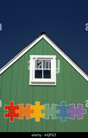 Little green house gable avec carré blanc peu de fenêtre et d'une scie sauteuse en pièces de puzzle couleurs arc-en-ciel Banque D'Images