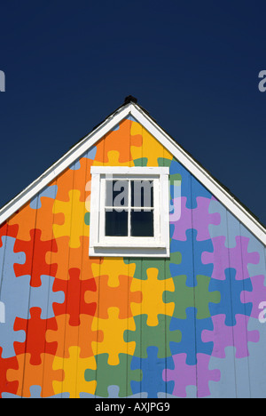 Little Blue House gable avec carré blanc peu de fenêtre et d'une scie sauteuse en pièces de puzzle couleurs arc-en-ciel Banque D'Images