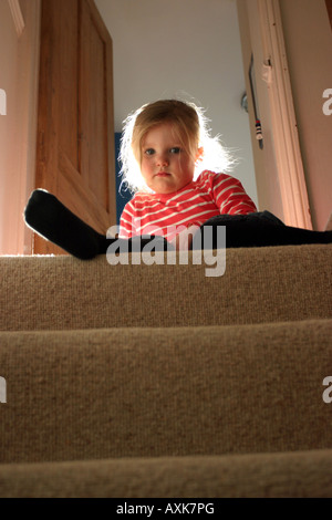 Enfant assis sur des escaliers Banque D'Images