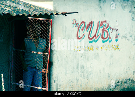 L'homme se cache dans un vieux hangar doorway avec Cuba signe sur mur, pris à Holguin, Cuba. Banque D'Images