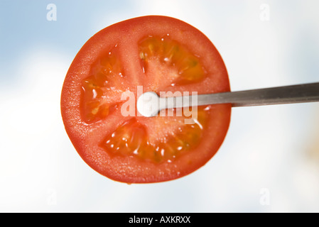 Tongs holding tranche de tomate, close-up Banque D'Images