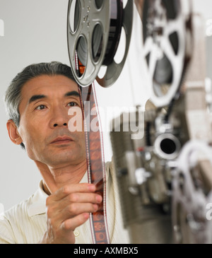 L'homme asiatique à la recherche de projecteur de film Banque D'Images