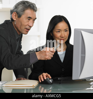 Asian businessman and businesswoman at computer Banque D'Images