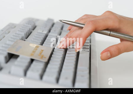 Close up of woman s hand holding pen avec carte de crédit et l'aide du clavier de votre ordinateur. Banque D'Images