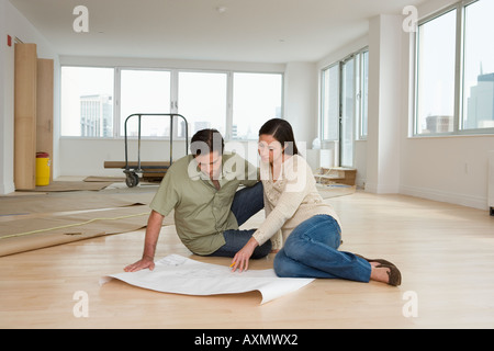 Couple looking at blueprints in new house Banque D'Images