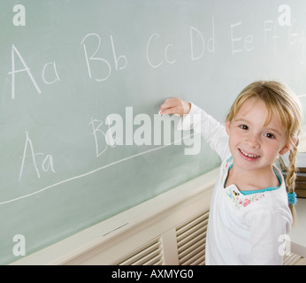 Girl writing on blackboard and smiling Banque D'Images